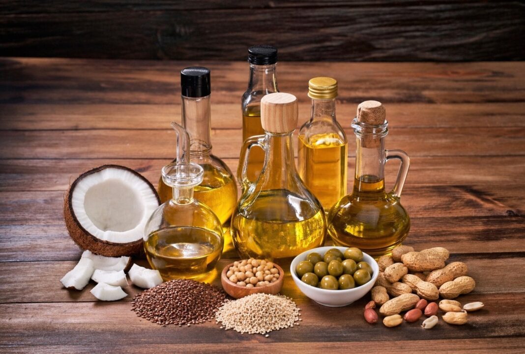 Botellas de diferentes aceites saludables, como oliva, coco y girasol, sobre una mesa de cocina.