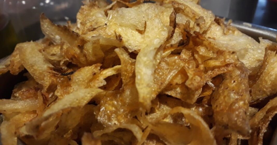 Preparación de fertilizante casero con cáscaras de papa y una botella de vinagre sobre una mesa de jardinería.