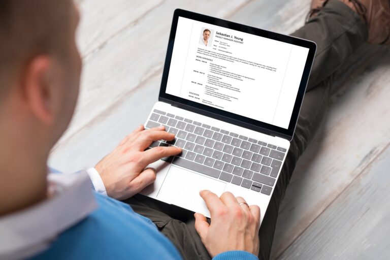 Persona utilizando una laptop para editar un currículum vitae con ayuda de herramientas digitales.