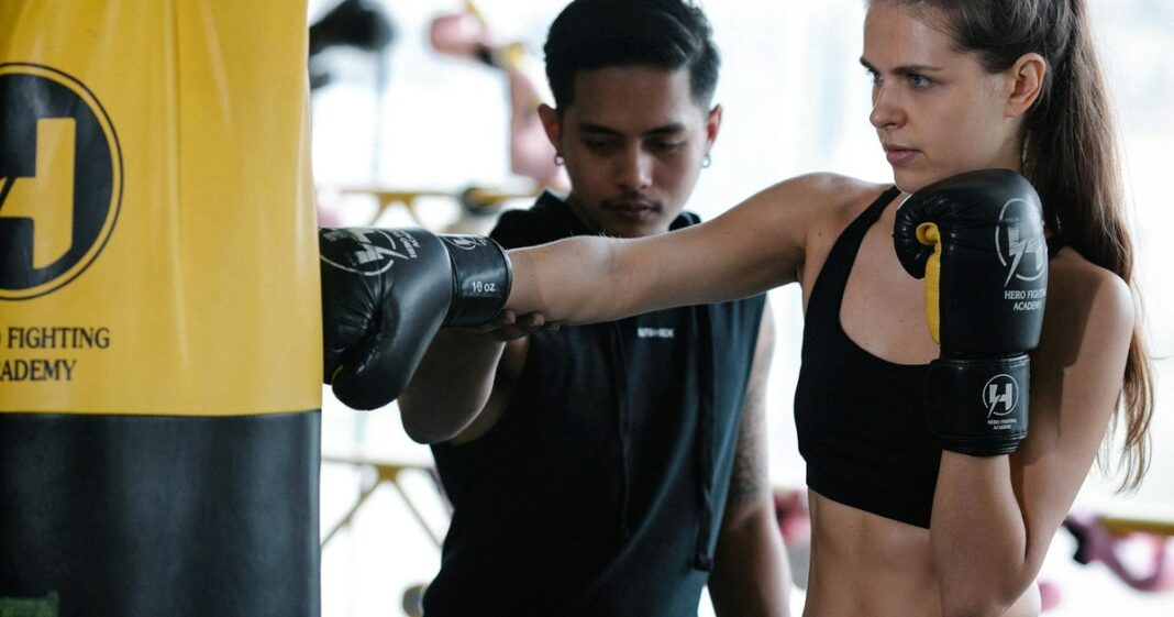 Adulto mayor realizando ejercicios de fuerza con mancuernas en un gimnasio, sonriendo.