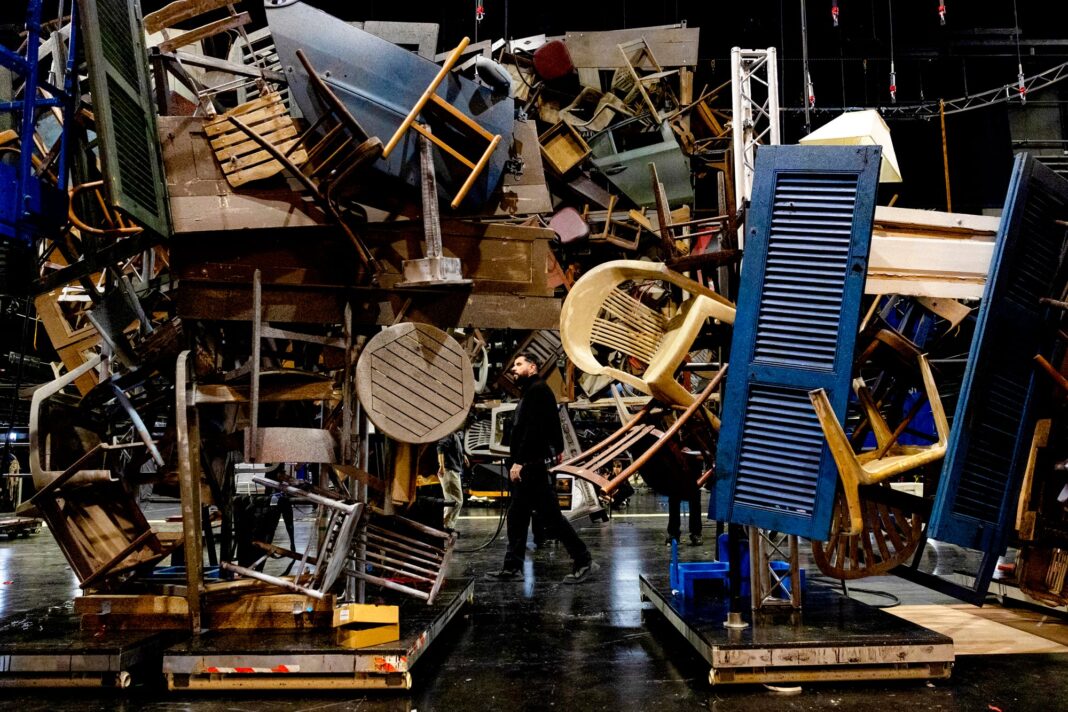 Instalación escenográfica compuesta por una gran pila de mesas, sillas y puertas antiguas en el Teatro Real de Madrid.