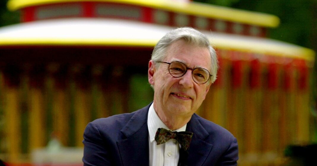 Fred Rogers, presentador de televisión, con su característico suéter rojo, sonriendo cálidamente.