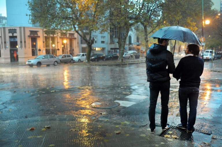 Calle anegada y vehículos transitando con dificultad durante la tormenta en el AMBA