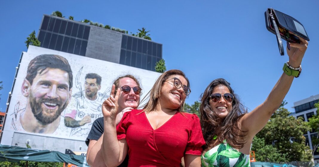 Vista de la costa de Miami con el Hard Rock Stadium al fondo y una multitud celebrando en South Beach