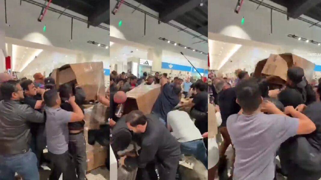 Multitud corriendo hacia pallets de cajas de iPhone 17 en shopping de Ciudad del Este