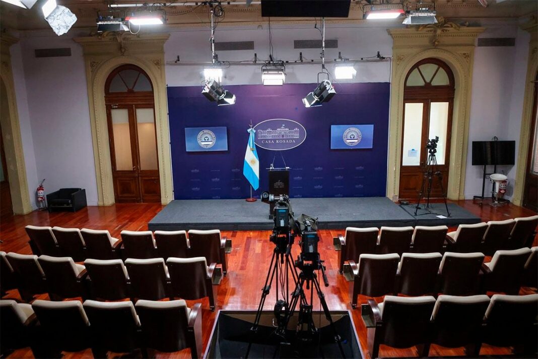 Sala de prensa de la Casa Rosada vacía con micrófonos y banderas argentinas